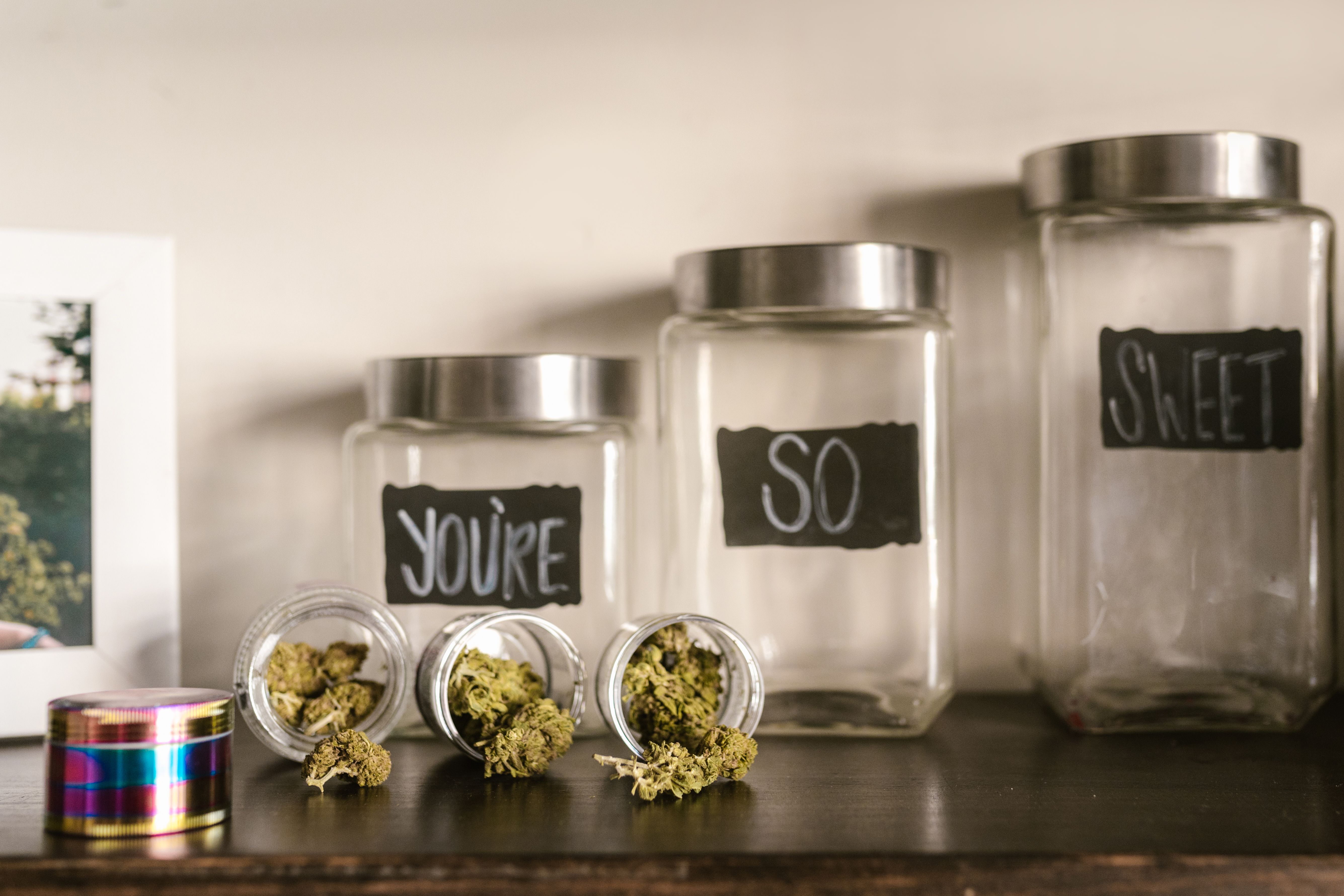 Branded glass jars filled with cannabis buds arranged on a shelf with playful product labels