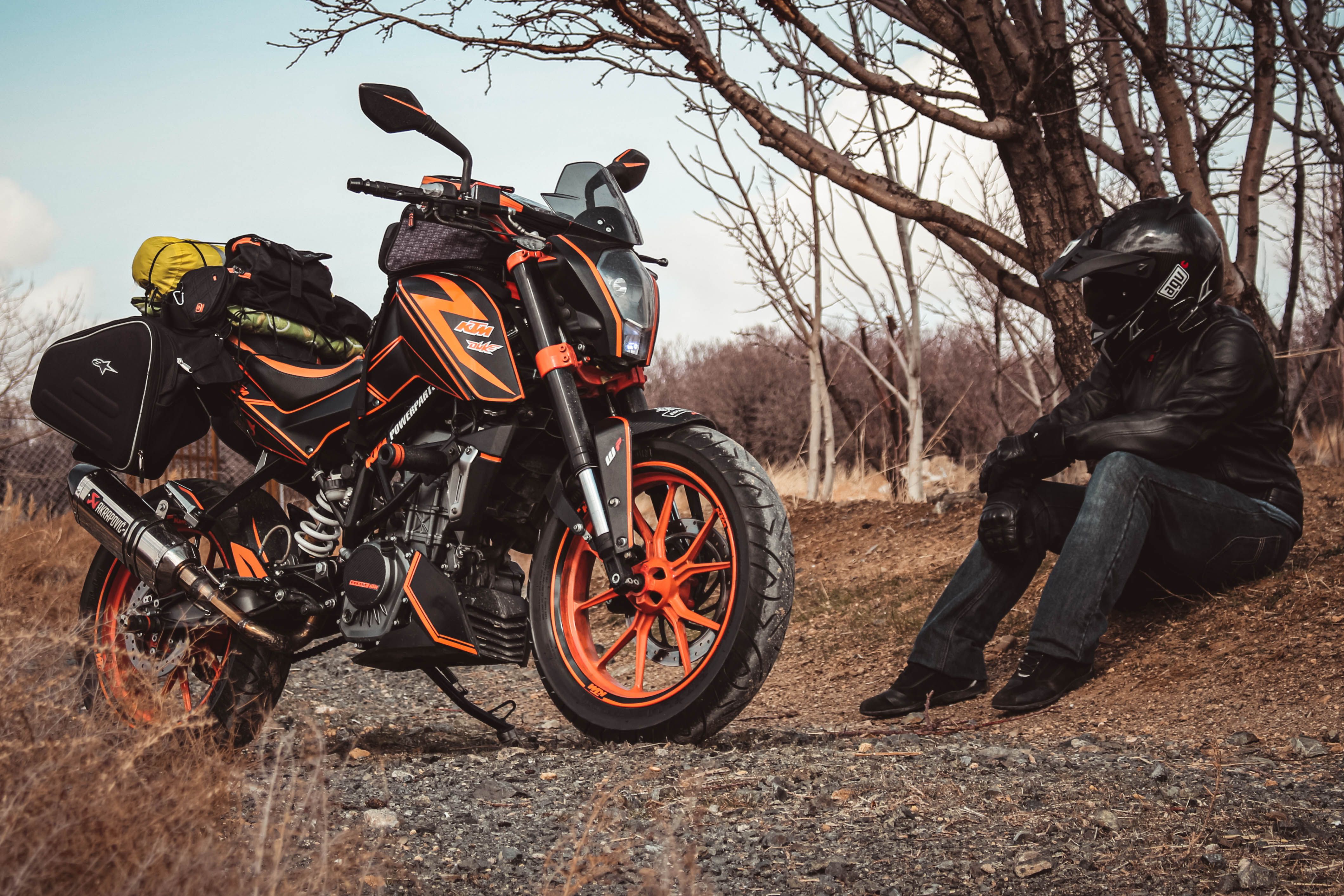 Motorcyclist resting beside a fully loaded touring bike on a rural route