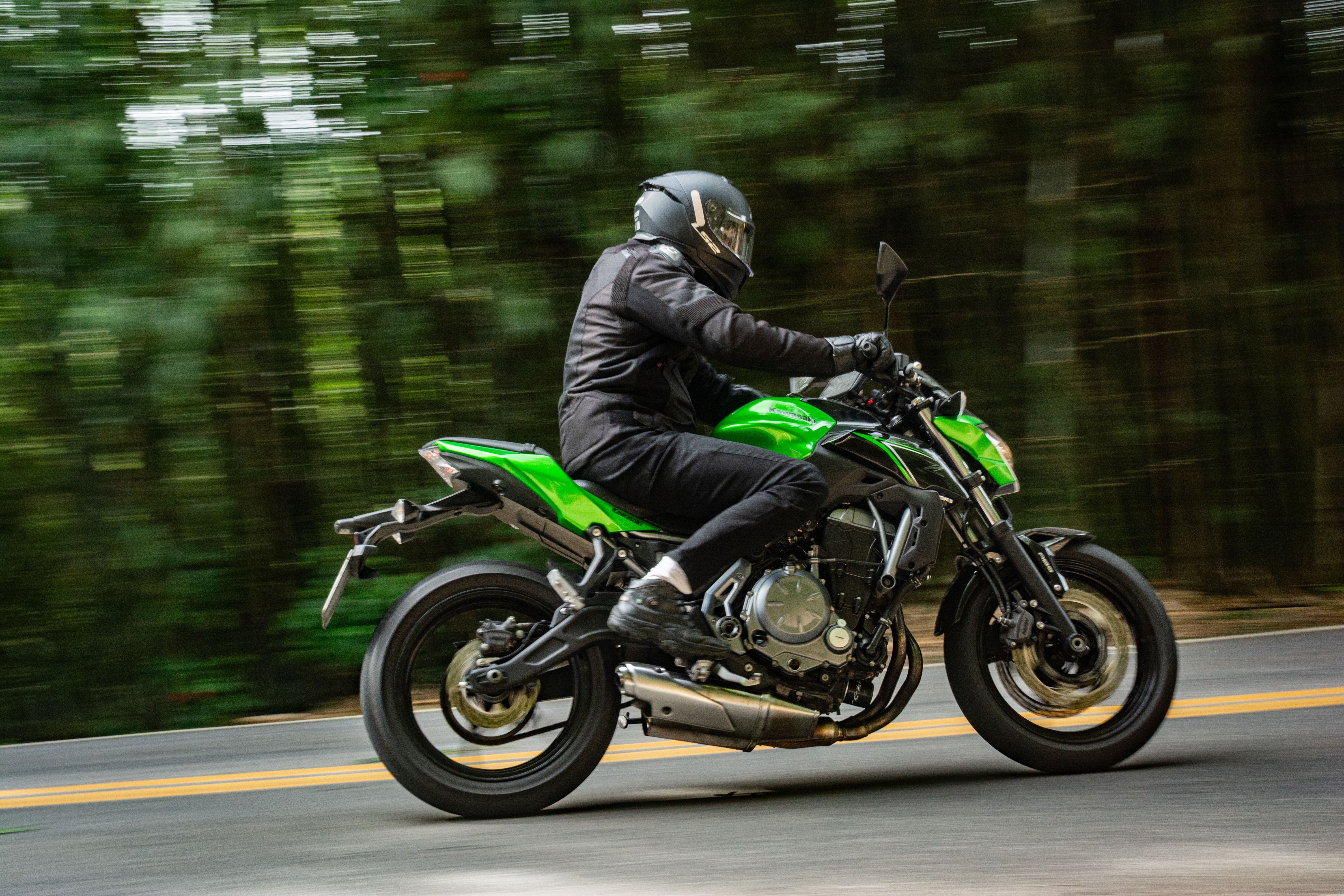 Rider in full protective motorcycle gear riding a forested back road