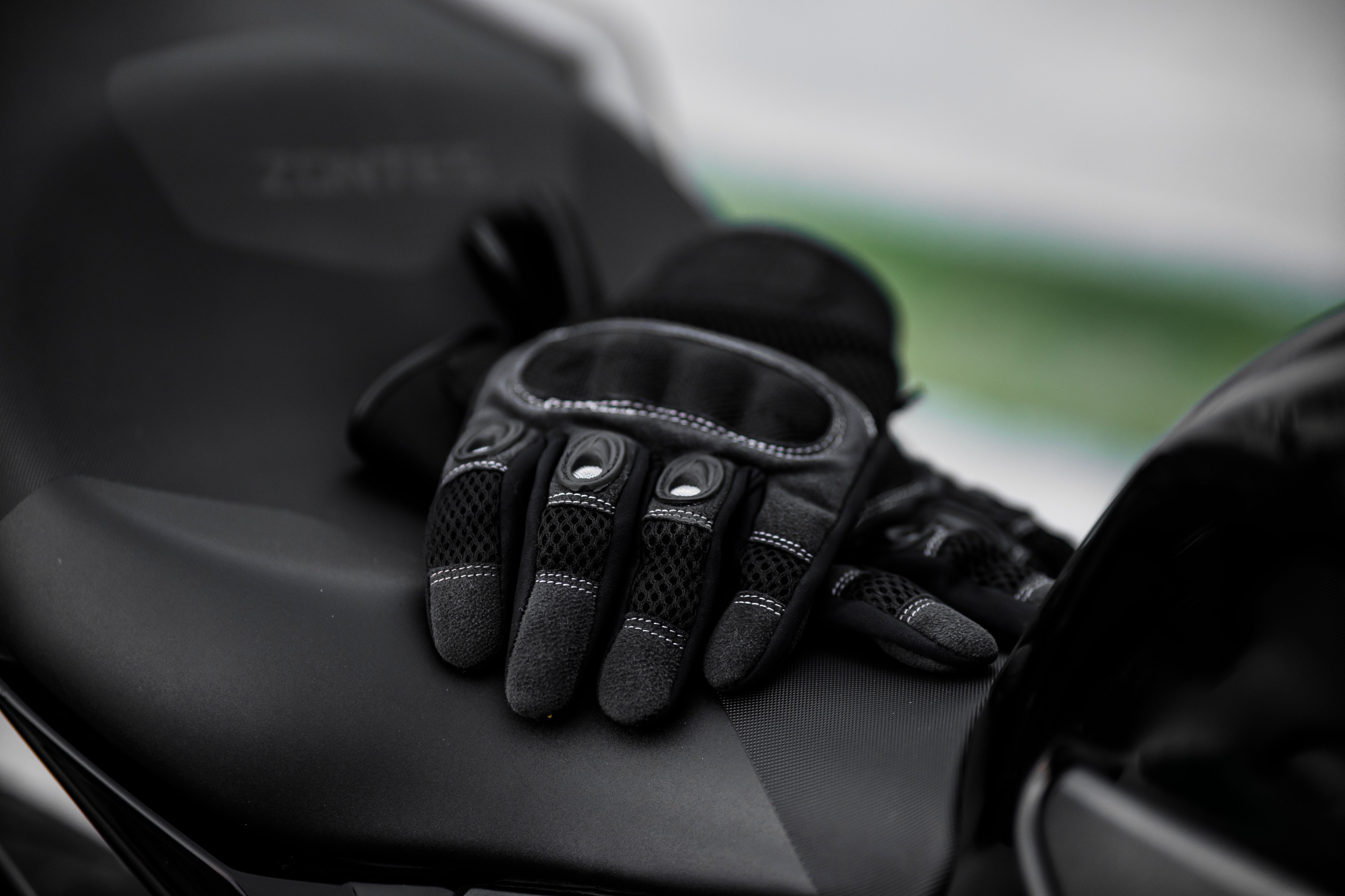 Close-up of padded black motorcycle touring gloves resting on a bike seat
