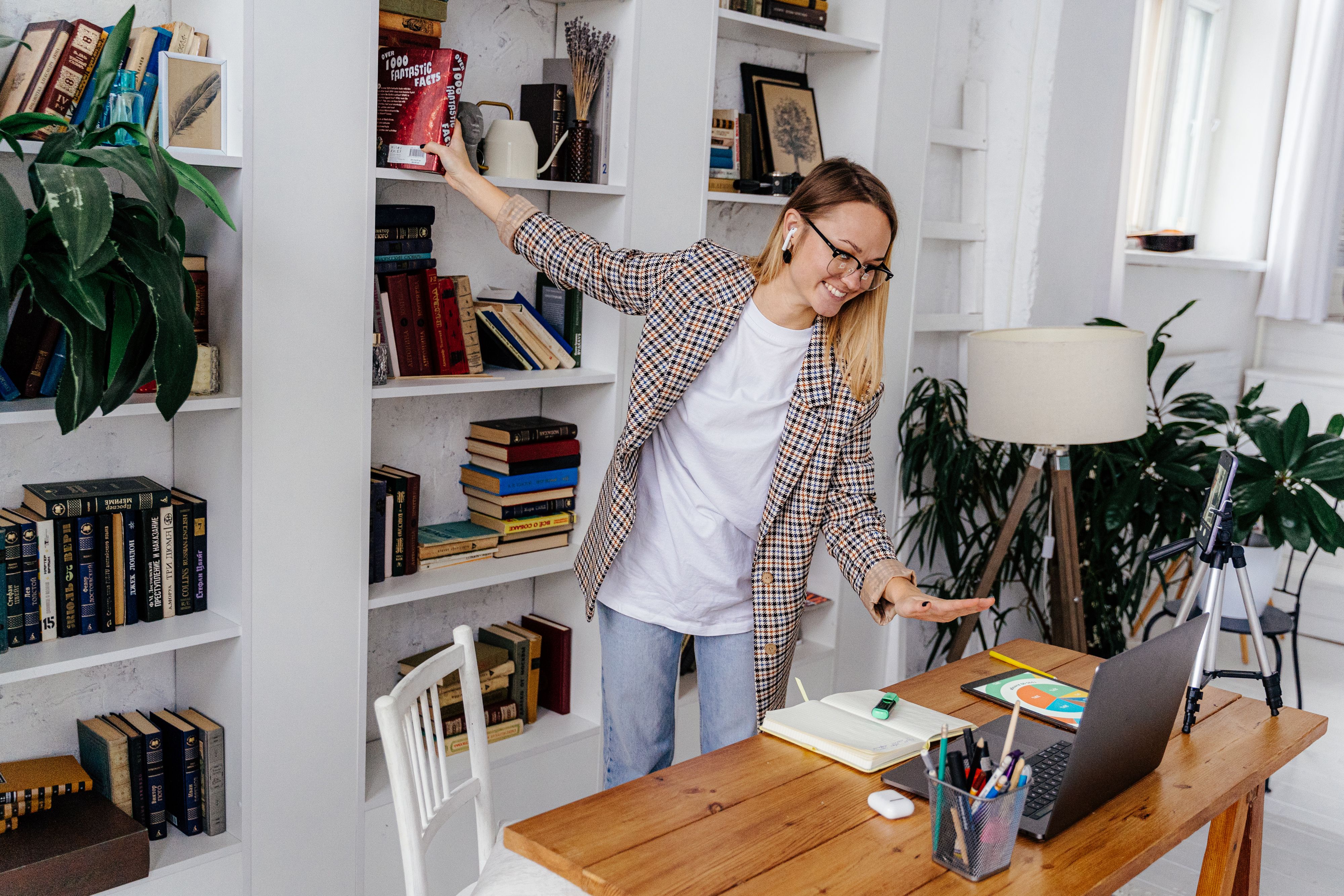Young woman wearing earphones and connecting through a video call from her home office.